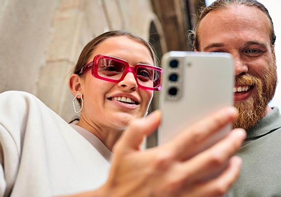 Digital Signage mit Magenta Business Zwei Personen lachen beim Blick auf ein Smartphone, Magenta Web SMS