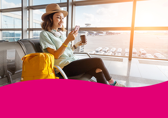 Roaming Junge Frau am Flughafen nutzt Smartphone und trinkt Kaffee – mobiles Surfen und Reisen mit digitaler Freiheit